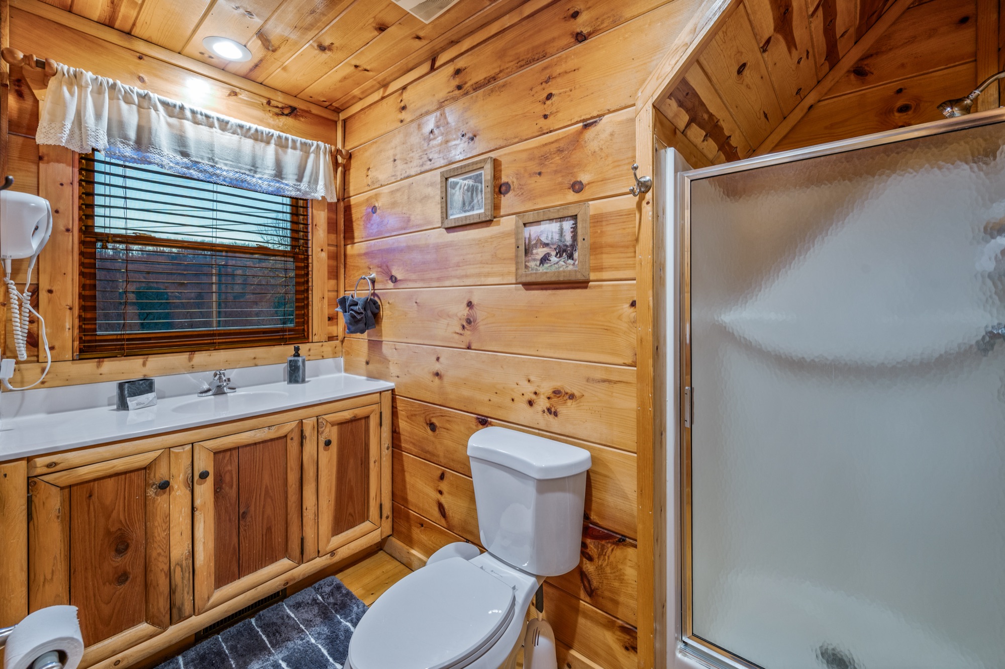 Loft ensuite bathroom at Bearadise with a vanity, framed prints, and a glass shower stall